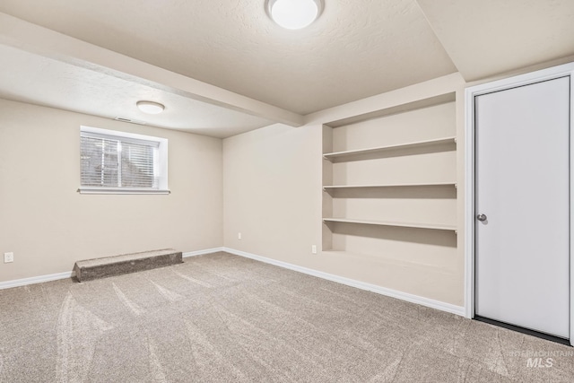 carpeted spare room with a textured ceiling and baseboards