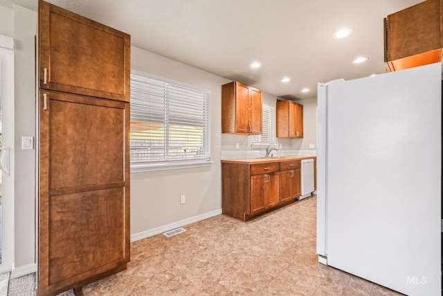 kitchen with baseboards, light countertops, recessed lighting, white appliances, and a sink