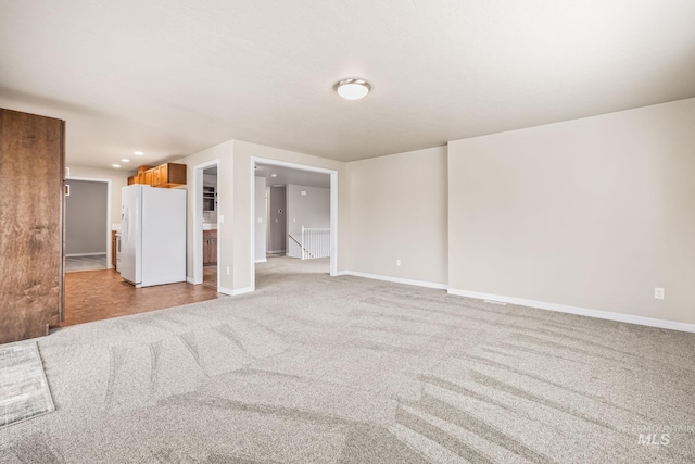 unfurnished living room with recessed lighting, baseboards, and light carpet