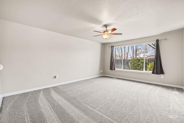 carpeted empty room featuring baseboards, a textured ceiling, and a ceiling fan