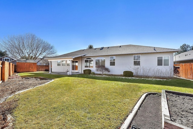 rear view of property with a garden, a fenced backyard, and a yard