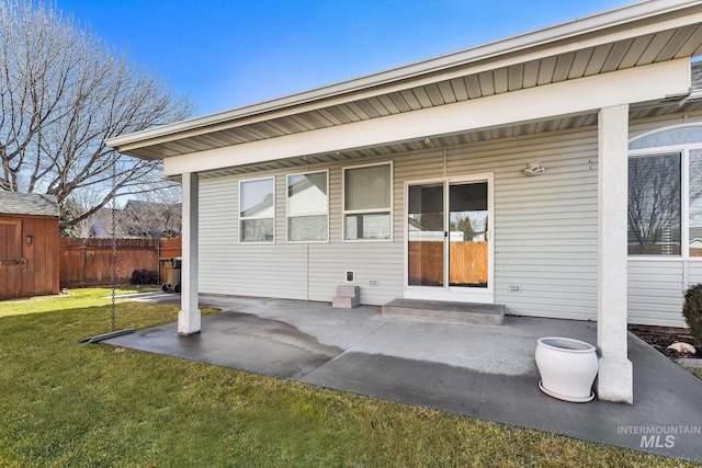 entrance to property featuring a patio area, a lawn, and fence