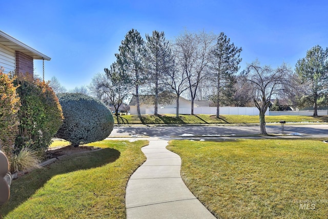 view of property's community featuring a lawn and fence