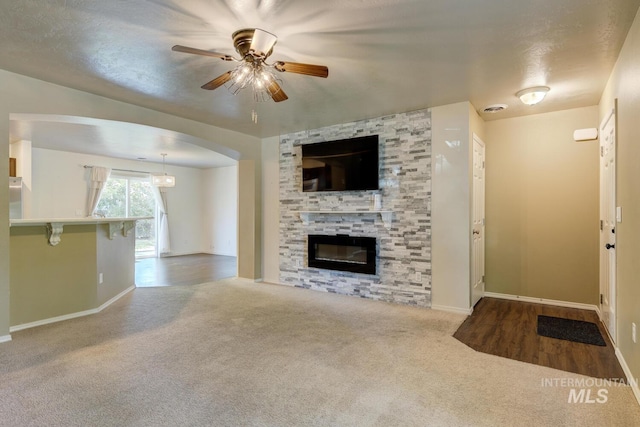 4935 N Rathbone Ave, Meridian, ID 83646 - unfurnished living room featuring carpet floors, ceiling fan, a fireplace, and arched walkways