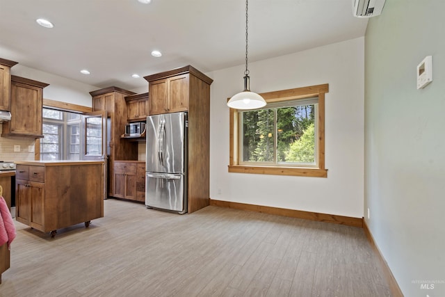 1649 Bear Trl, Donnelly, ID 83615 - kitchen featuring stainless steel appliances, brown cabinetry, light wood-style floors, a wall mounted air conditioner, and hanging light fixtures