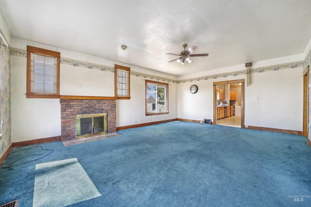 unfurnished living room with ceiling fan, a fireplace, and carpet