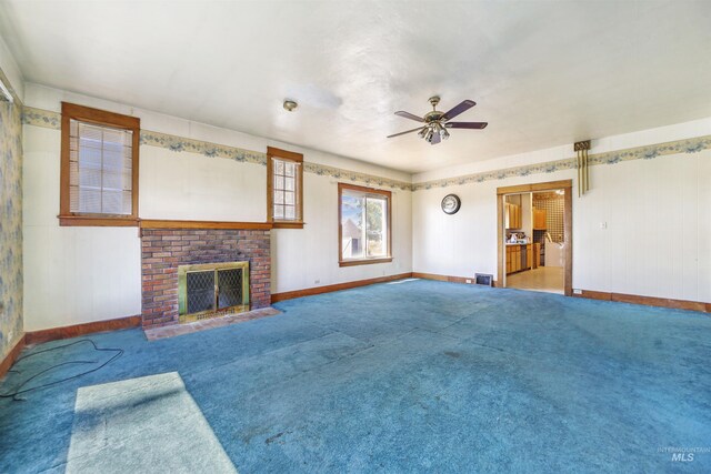 unfurnished living room featuring a brick fireplace, carpet flooring, and ceiling fan