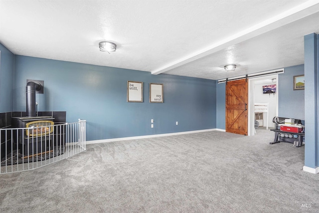 basement with carpet flooring, a barn door, a textured ceiling, and a wood stove