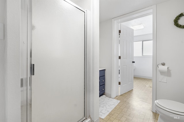 bathroom featuring a shower with door, vanity, and toilet