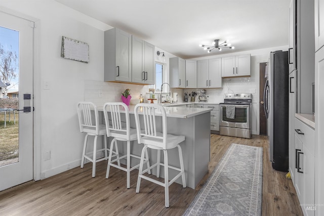 kitchen with a breakfast bar, sink, decorative backsplash, kitchen peninsula, and stainless steel appliances