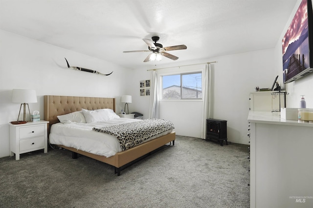 carpeted bedroom with a wood stove and ceiling fan