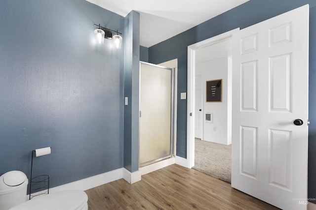 bathroom featuring walk in shower, hardwood / wood-style floors, and toilet