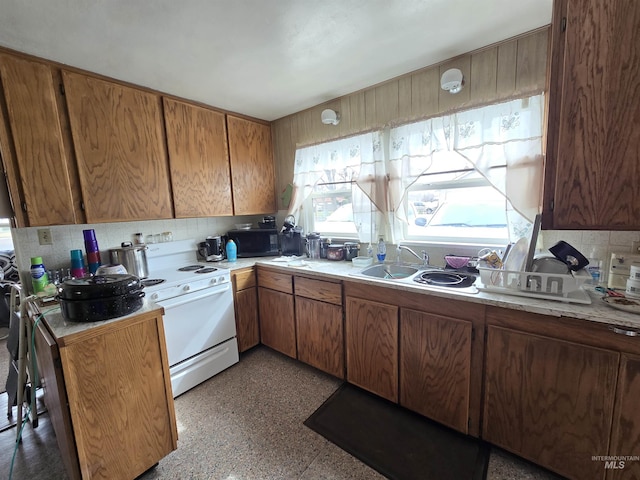 kitchen with brown cabinetry, a sink, light countertops, black microwave, and tasteful backsplash