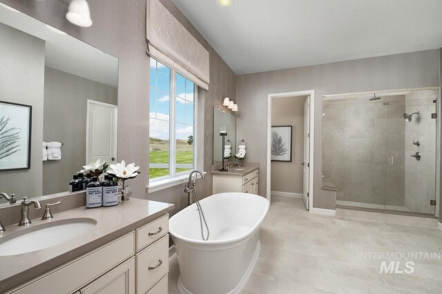 full bathroom featuring two vanities, a sink, a stall shower, and a soaking tub