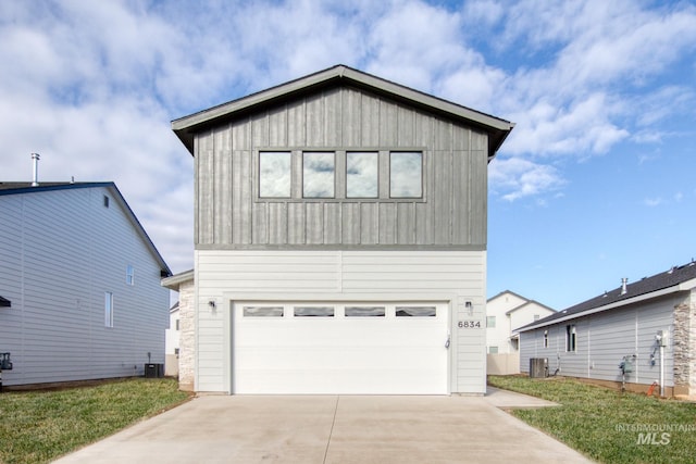 view of front facade with central air condition unit, driveway, an attached garage, and a front lawn