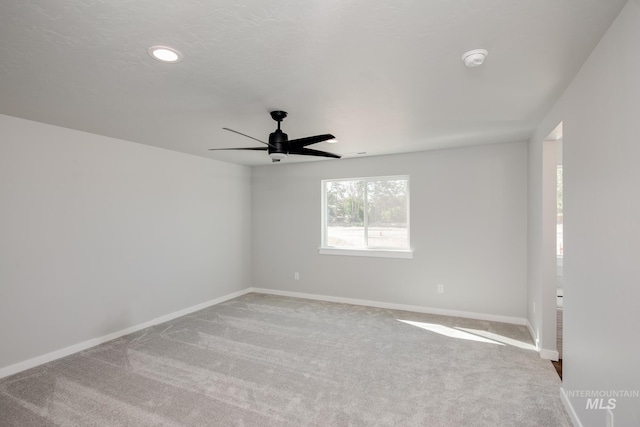 spare room with carpet, a ceiling fan, and baseboards