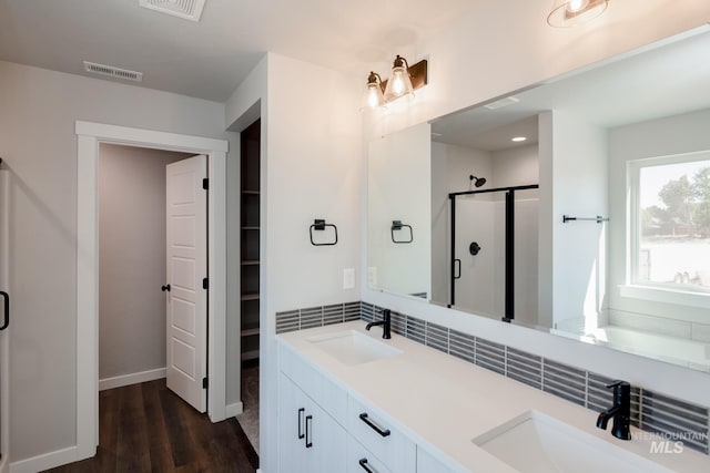 full bathroom with visible vents, a stall shower, wood finished floors, and a sink