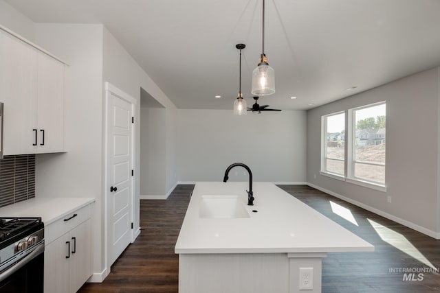 kitchen with light countertops, dark wood-type flooring, stainless steel range with gas cooktop, and a sink