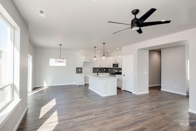 kitchen featuring open floor plan, appliances with stainless steel finishes, a ceiling fan, and a kitchen island with sink