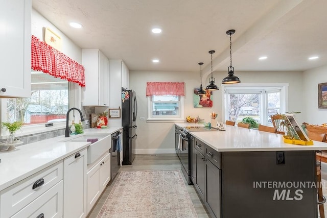 kitchen featuring stainless steel appliances, sink, pendant lighting, light hardwood / wood-style flooring, and white cabinetry