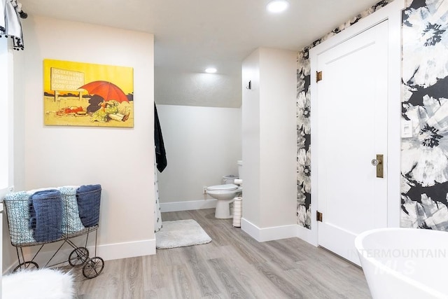 bathroom featuring a bath, hardwood / wood-style flooring, and toilet