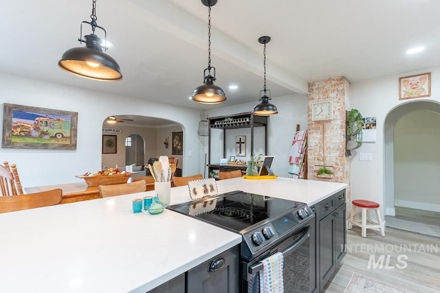 kitchen featuring ceiling fan, beamed ceiling, black electric range, light hardwood / wood-style floors, and hanging light fixtures