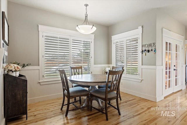 dining room with wainscoting, a healthy amount of sunlight, and wood finished floors