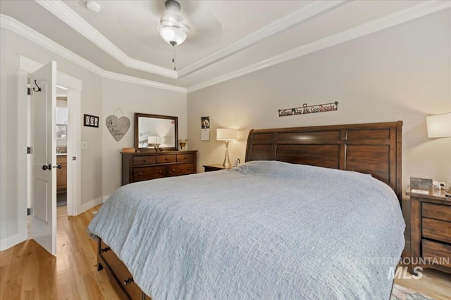 bedroom with crown molding, baseboards, light wood-type flooring, a raised ceiling, and a ceiling fan