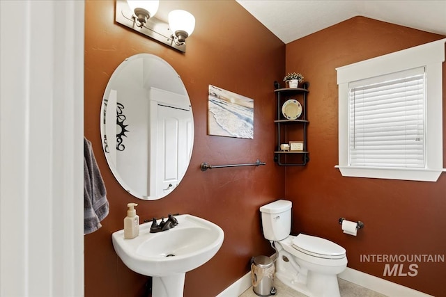 half bath with a sink, baseboards, lofted ceiling, and toilet