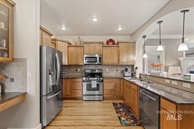 kitchen featuring decorative backsplash, dark stone countertops, appliances with stainless steel finishes, and a sink