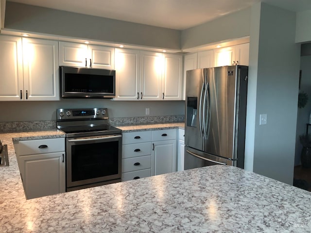 kitchen featuring white cabinetry, light stone counters, and stainless steel appliances