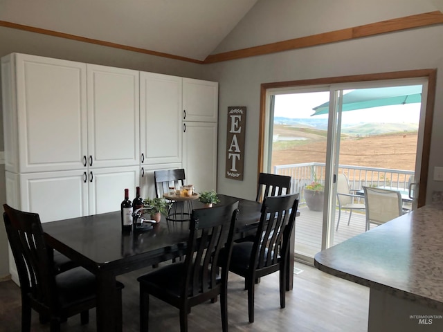 dining room with vaulted ceiling and light hardwood / wood-style floors