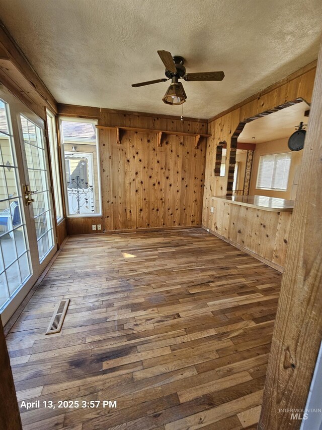 314 S Phillippi St, Boise, ID 83705 - unfurnished room featuring a textured ceiling, wood-type flooring, plenty of natural light, wooden walls, and a ceiling fan
