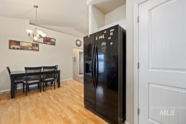 kitchen with lofted ceiling, light hardwood / wood-style flooring, a chandelier, hanging light fixtures, and black fridge with ice dispenser