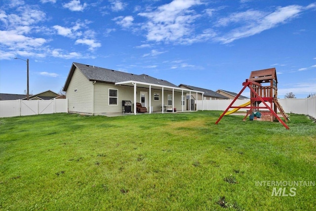 back of house featuring a yard and a playground