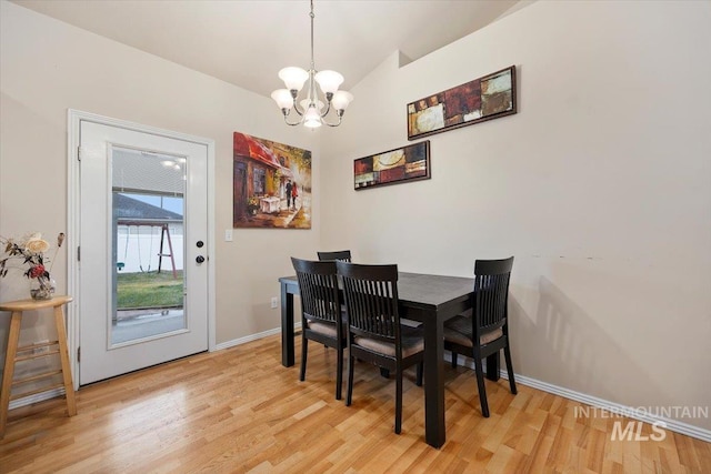 dining room with vaulted ceiling, an inviting chandelier, and light wood-type flooring