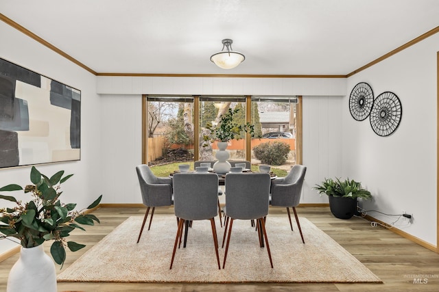 dining room featuring crown molding, baseboards, and wood finished floors