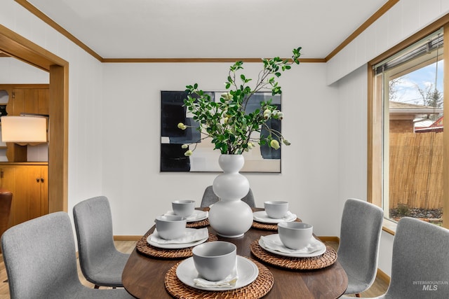 dining space with crown molding, baseboards, and wood finished floors
