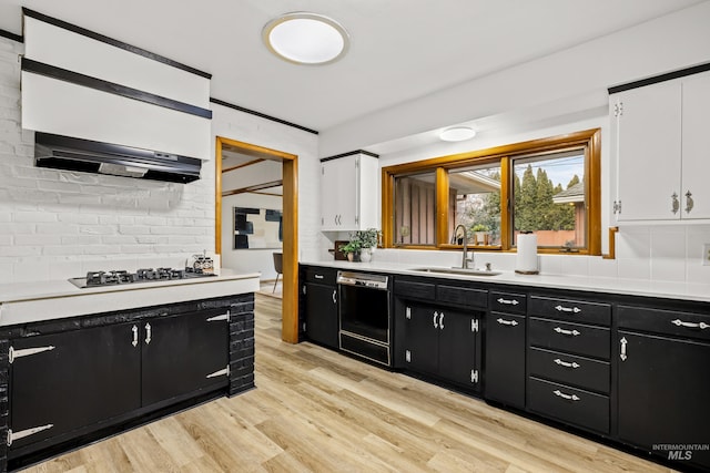 kitchen with dark cabinetry, a sink, white cabinets, and black appliances