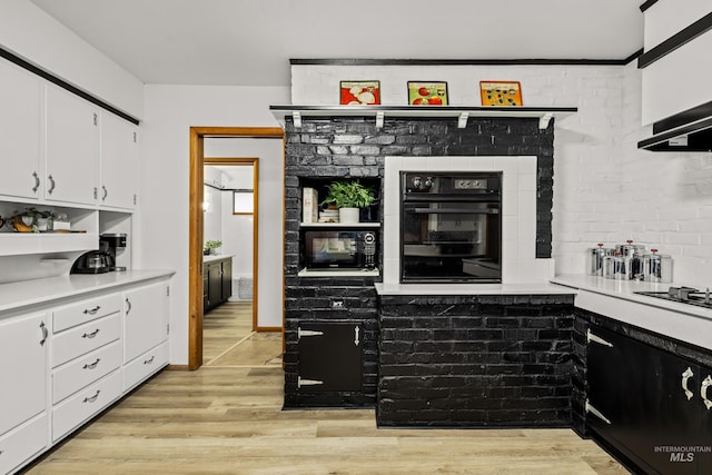 kitchen with light countertops, white cabinets, black appliances, and light wood finished floors