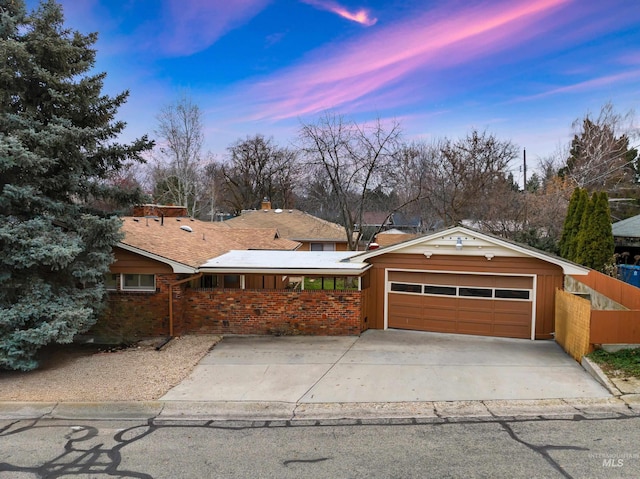 ranch-style home featuring fence, a garage, driveway, and brick siding