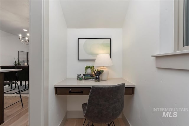 office area with built in study area, baseboards, and wood finished floors