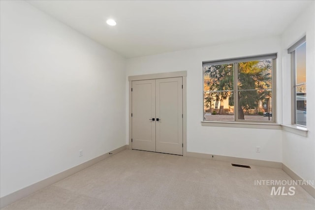 carpeted empty room featuring visible vents, recessed lighting, and baseboards