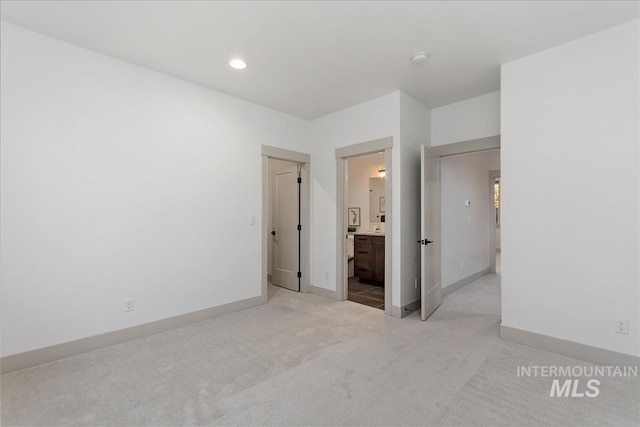 unfurnished bedroom featuring recessed lighting, baseboards, light carpet, and ensuite bathroom