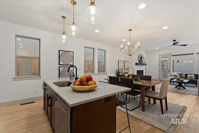 kitchen featuring visible vents, a sink, open floor plan, light wood-style floors, and dishwasher