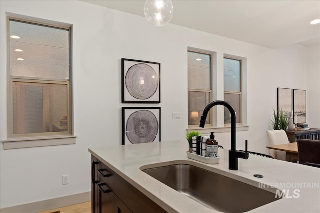 kitchen featuring light countertops, dark brown cabinetry, and a sink