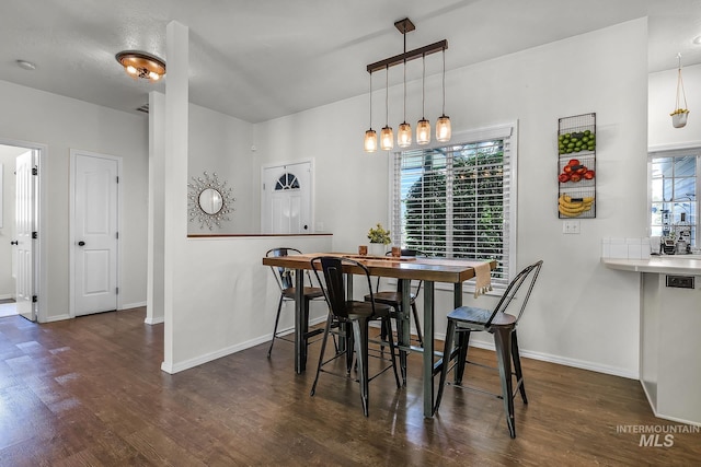 dining space with dark wood-style flooring and baseboards