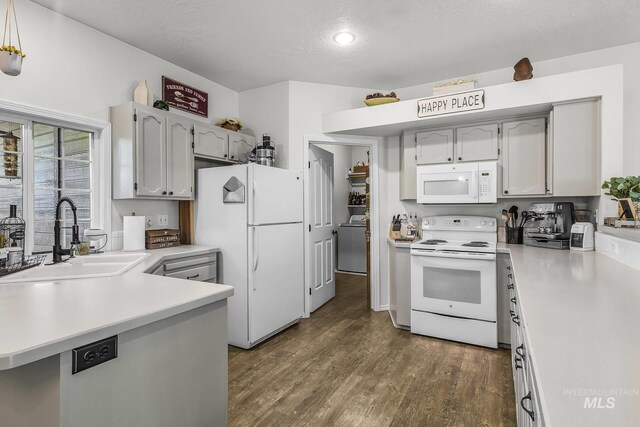 kitchen featuring a sink, white appliances, light countertops, dark wood finished floors, and washer / dryer