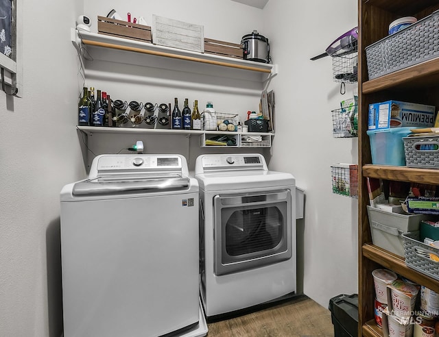 clothes washing area with laundry area, washer and clothes dryer, and wood finished floors