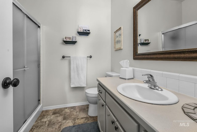 full bathroom featuring toilet, baseboards, a shower stall, and vanity